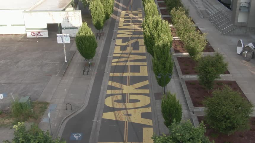 Black lives matter painted in yellow paint on a street