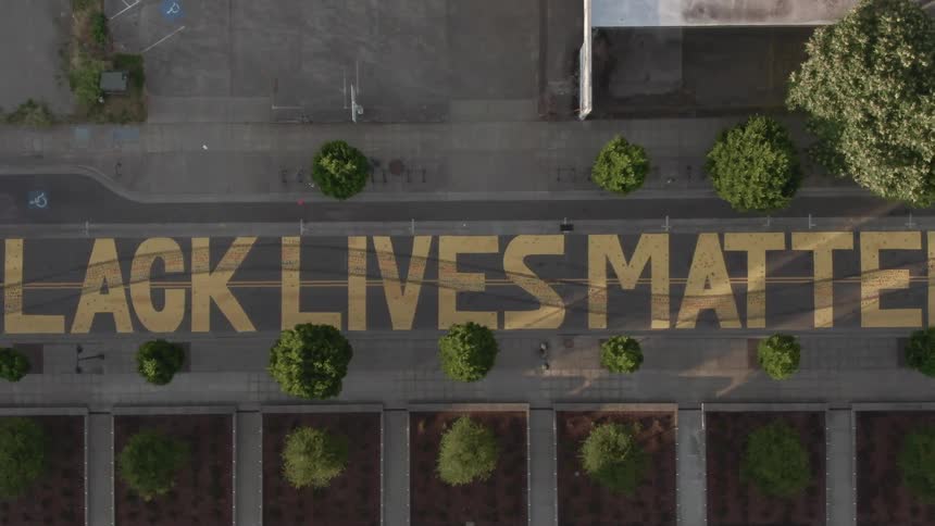 Black lives matter painted in yellow paint on a street
