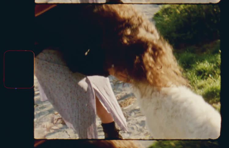 A woman with a guitar on her back pets a dog