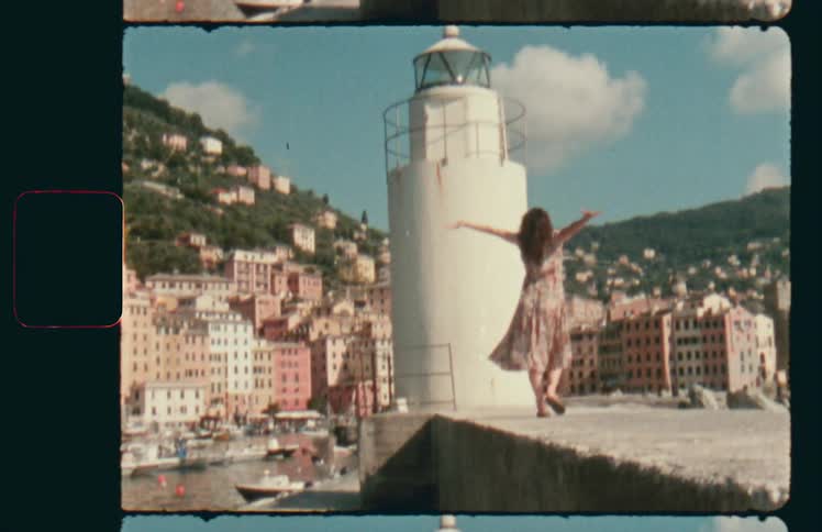 A woman walks along a pier and throws her arms in the air