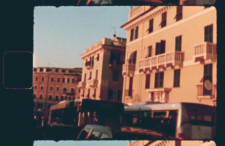 Buses move by a three story neighborhood building