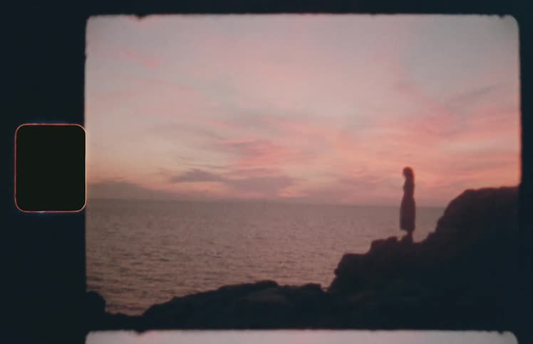 A woman stands on a cliff on the shore