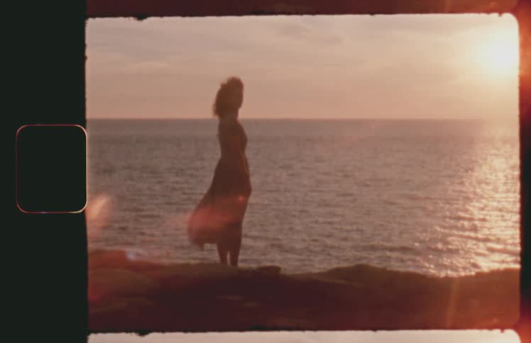 Woman overlooks the ocean as the sun rises