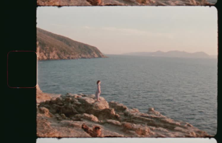 Woman standing on rocks overlooking the coast on a windy day