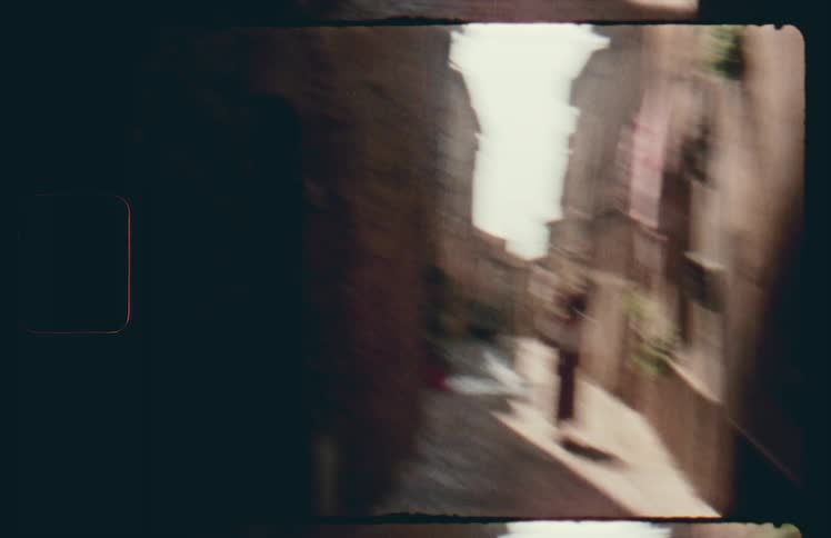 Shaky camera movement as if running towards woman walking down alley