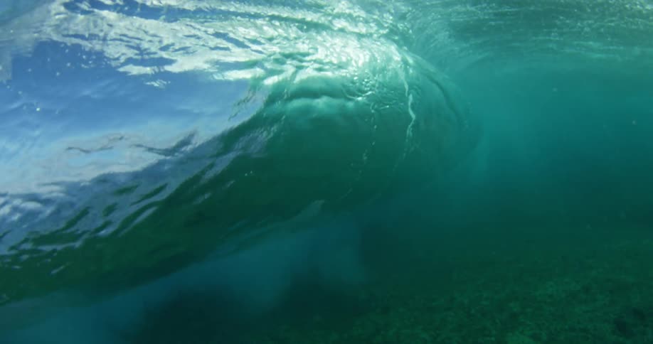 The ocean underwater with waves with the sky and clouds above