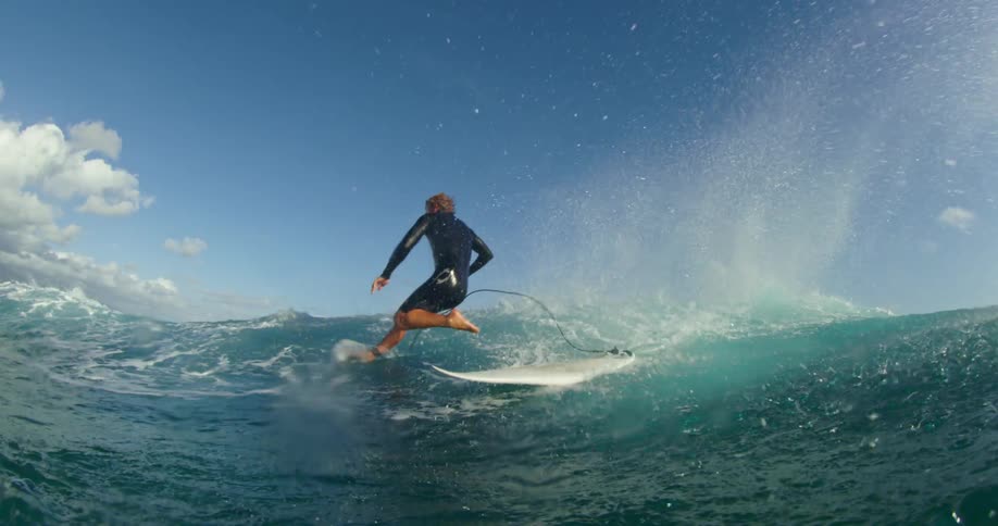 A man surfing in the ocean and falling off the board