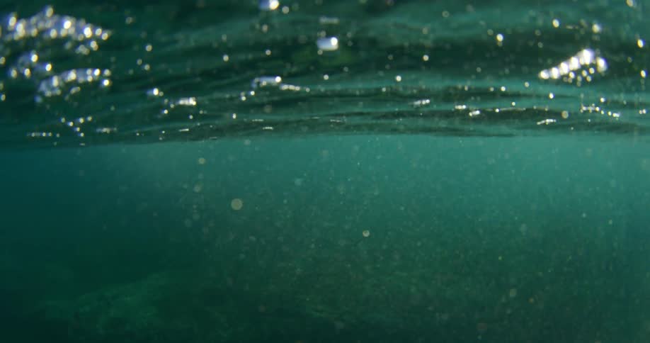 An ocean with water and bubbles with the sky and clouds above