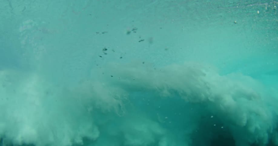 An underwater view of an ocean wave crashing down