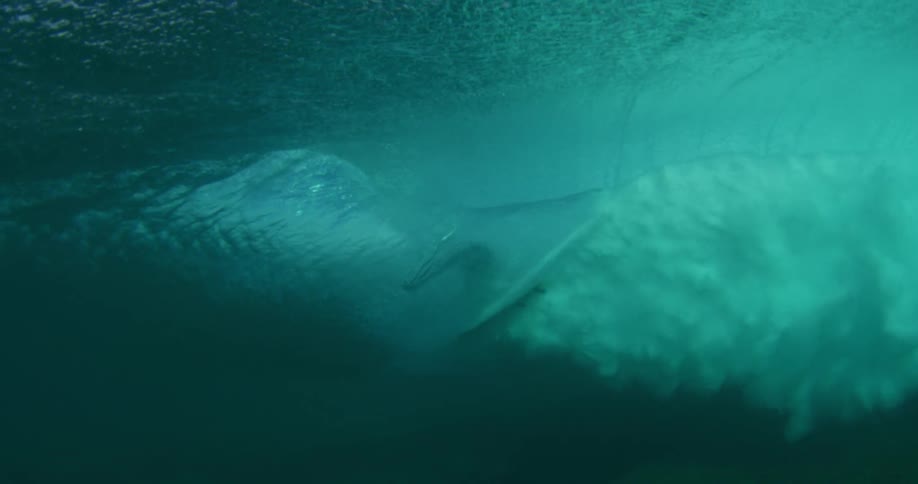 Surfers getting barreled and can be seen surfing through wave from underwater