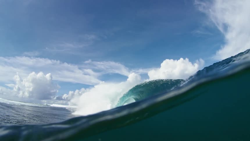 An ocean wave crashing down into a sea in the daytime