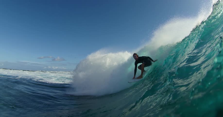 Surfer rides a huge wave under a cloudy sky and is seen from underwater
