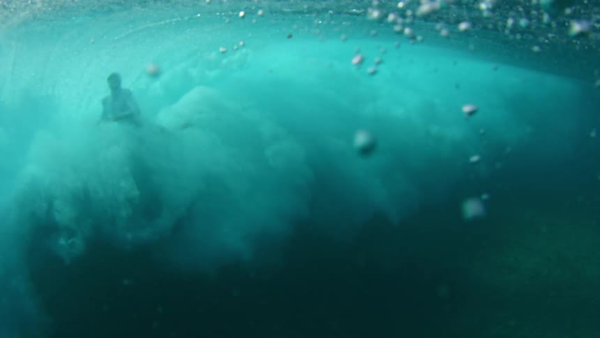 Underwater footage of a man being swept by an ocean wave