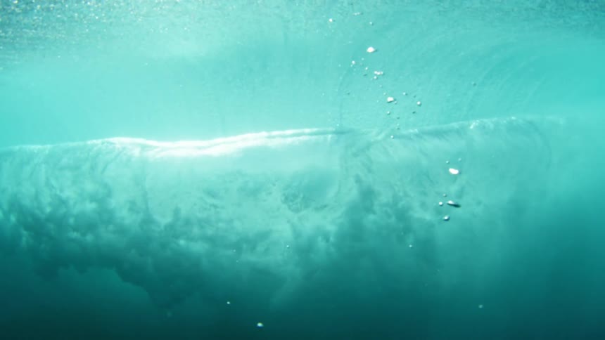 Underwater view of water rippling and the sky shining through