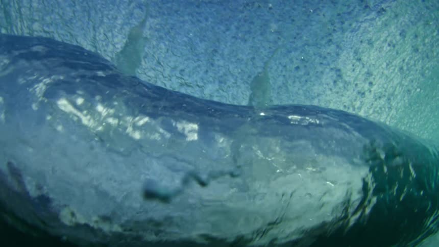 An ocean wave crashes over a camera on the ocean during the day