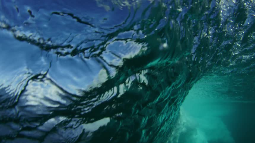 An ocean wave crashing down in water on a sunny day