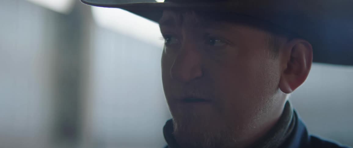 A portrait of a man putting on a cowboy hat