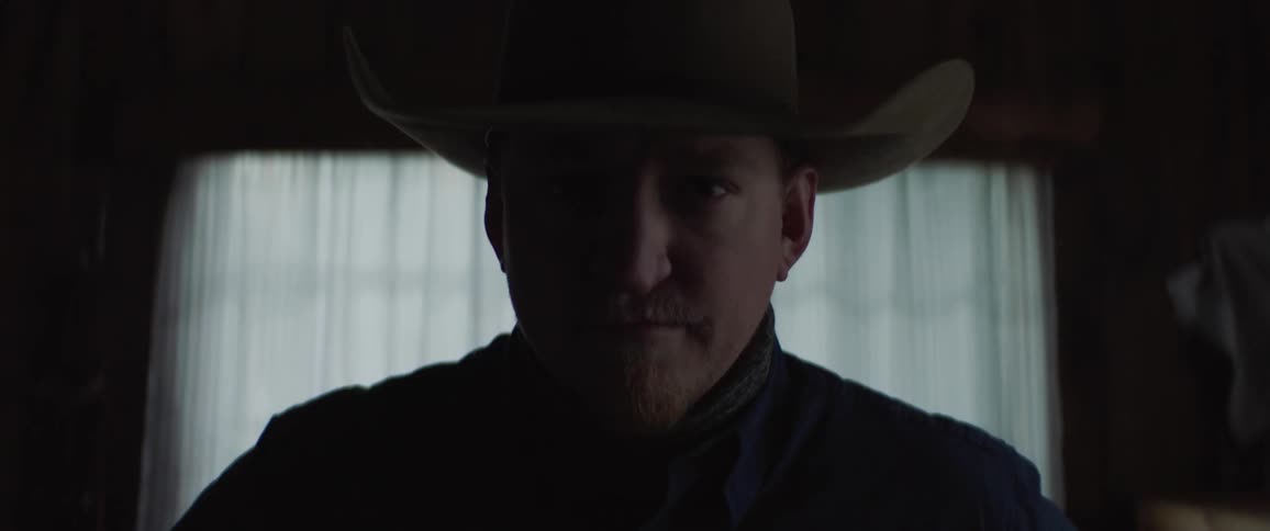 A cowboy lifts his head and looks straight ahead
