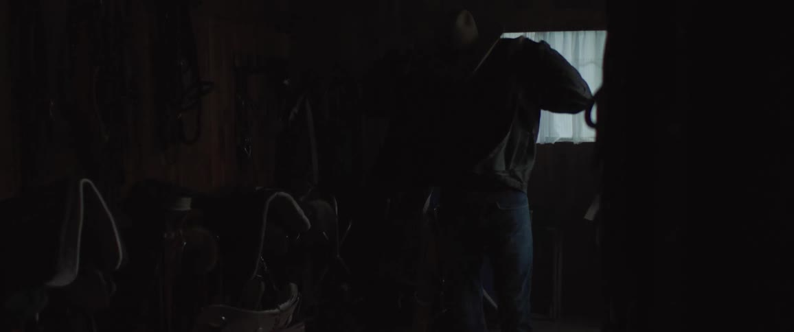 A cowboy puts on his jacket and leaves the room