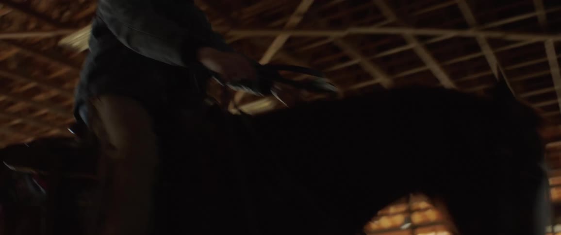 A man struggles riding a horse inside a large stable