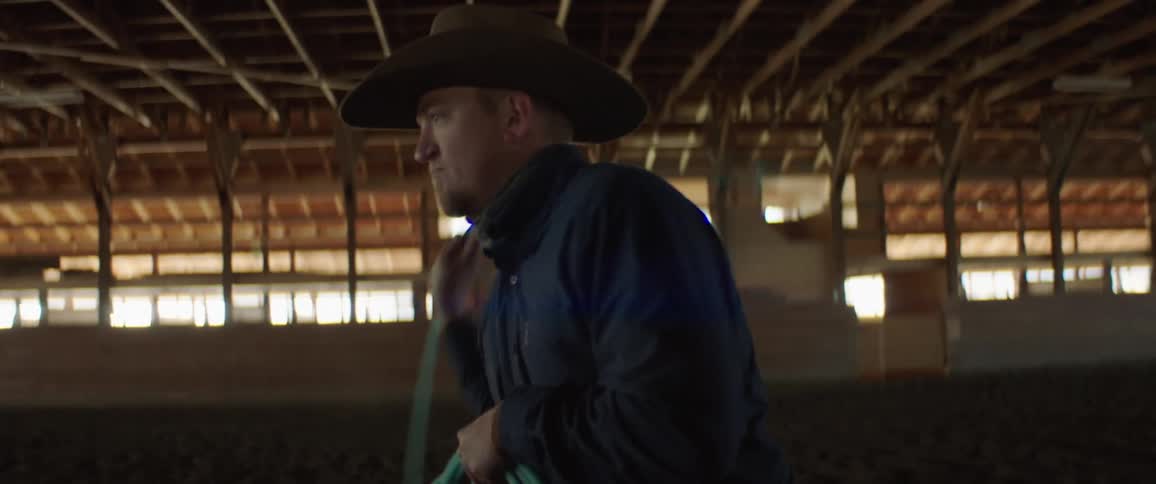 A man swinging a lasso in a barn
