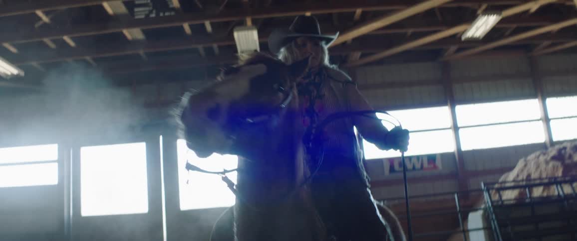 A woman riding a horse in a barn