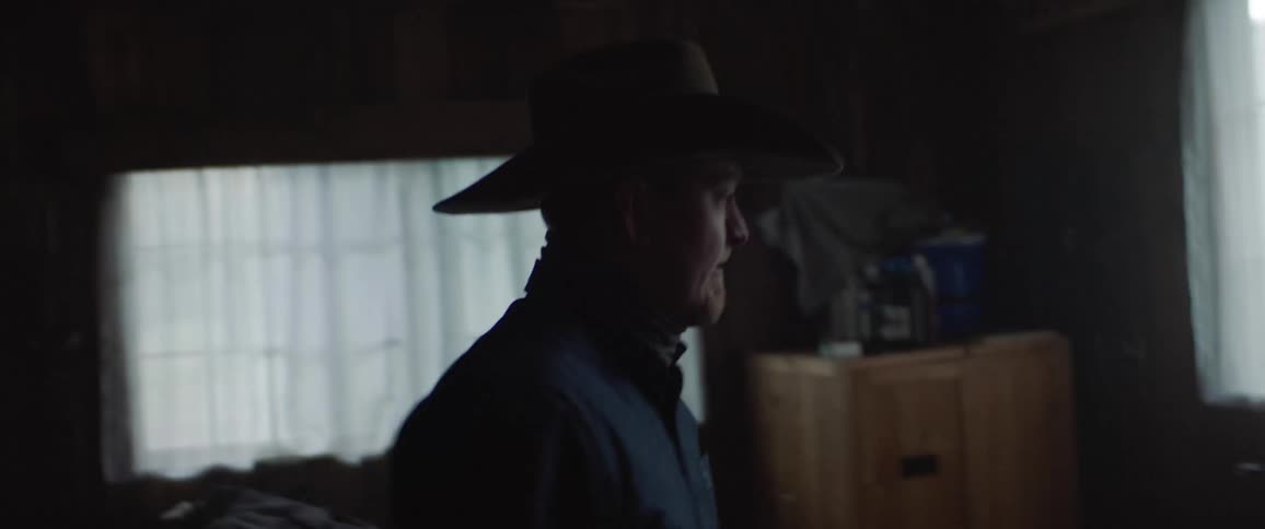 Man putting away saddles in dimly lit building