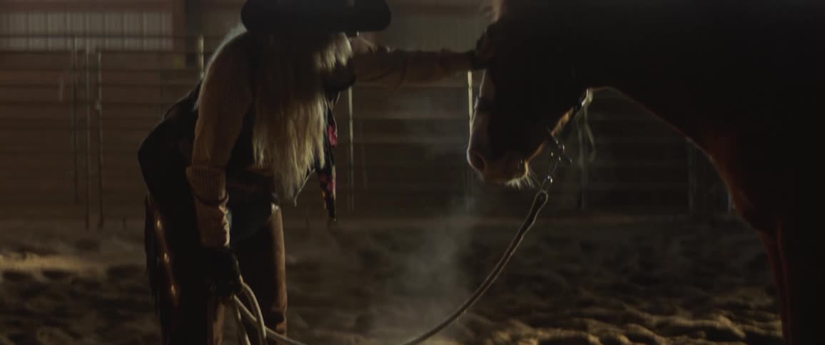 A woman petting a horse on their face in a barn