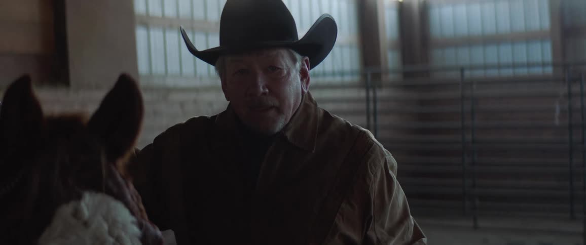 Older man stands in indoor horse arena next to horse