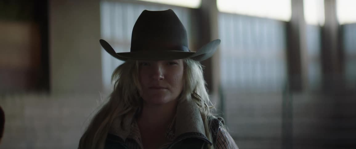 A woman posing for a portrait while wearing a cowboy hat