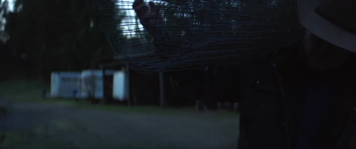 A man on a farm carrying wire around