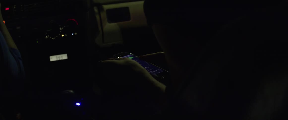 A passenger in a car scrolls through her phone