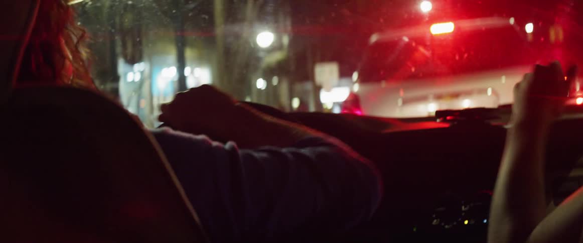 Two women driving and singing and dancing in a car