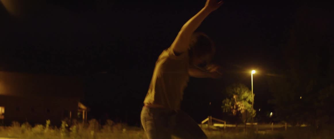 A man is skateboarding in the parking lot