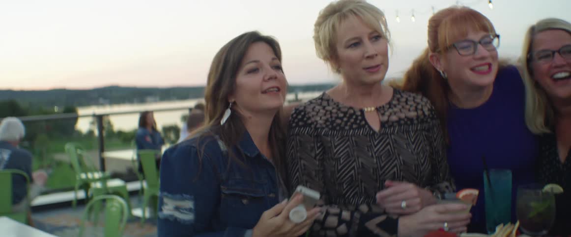 Women gather to take a photo at a rooftop bar