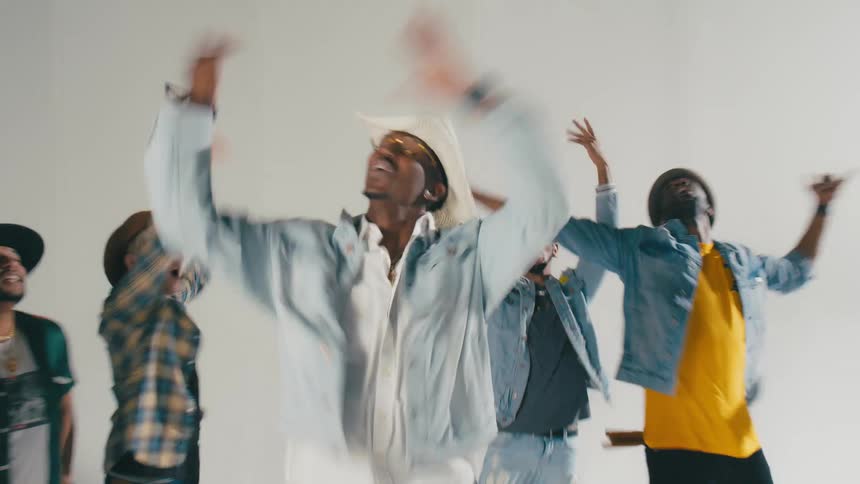 Group of young people energetically dancing in front of a white background