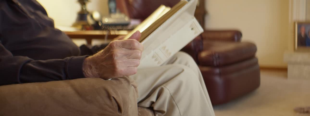 An elderly person looking at a photo album while sitting in a living room