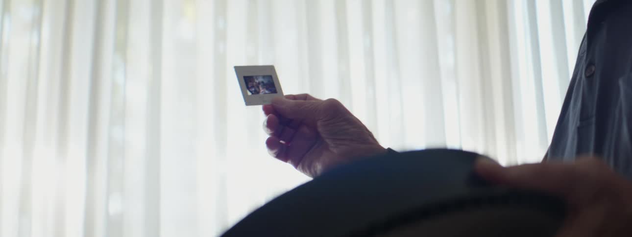 A person holding up a vintage 35mm slide from a slide carousel