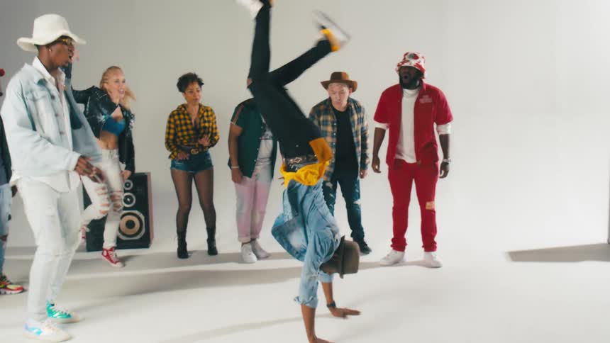 Men and women dancing with a wall and speakers in the background