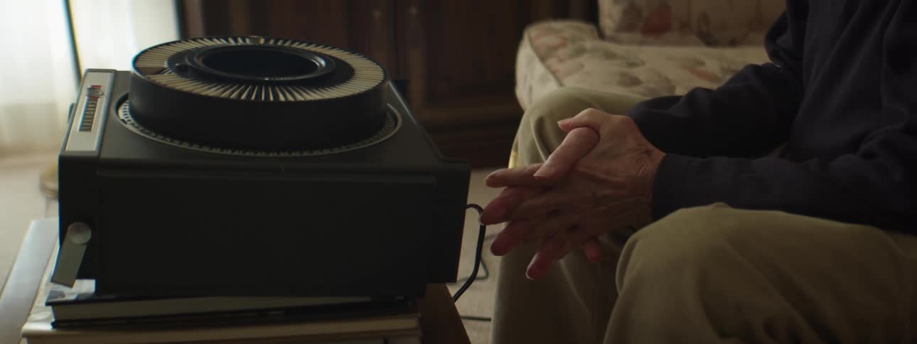 A person sitting on a couch looking at slides on a projector