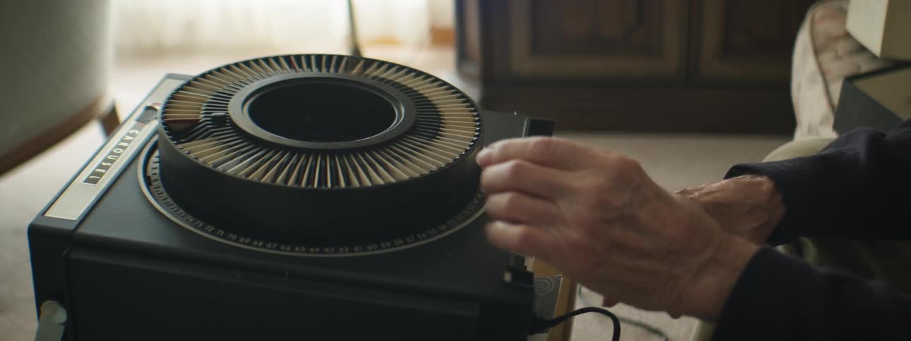 Elderly man arranging slides on a carrousel projector in the living room at home