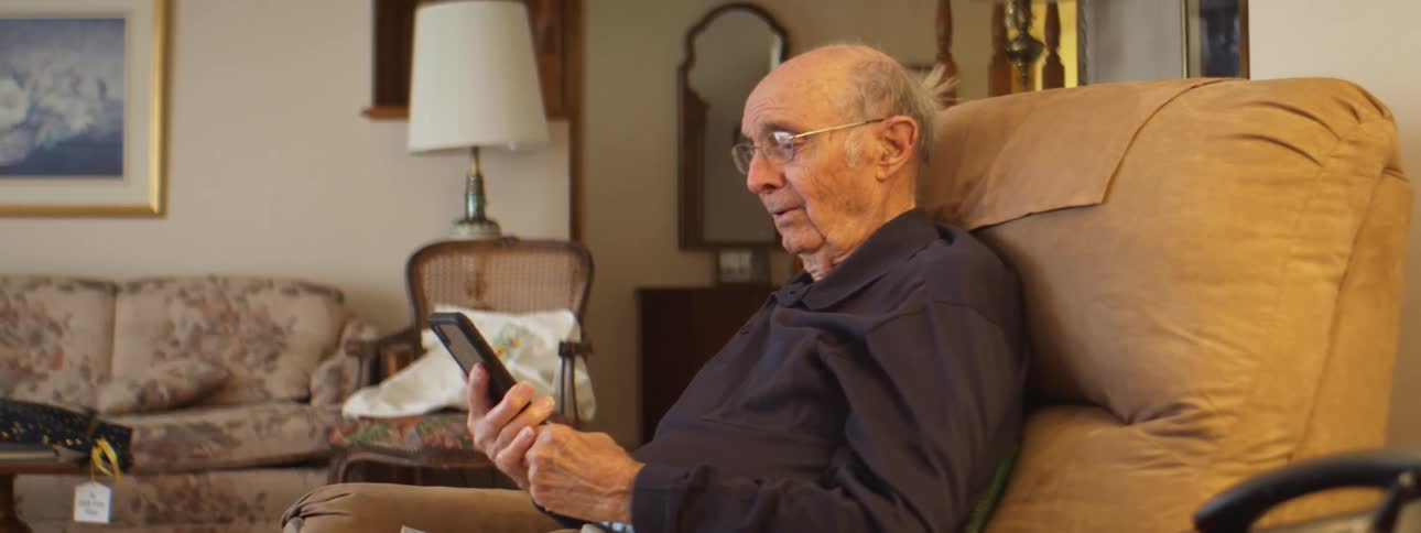 A man that is holding a smartphone and relaxing