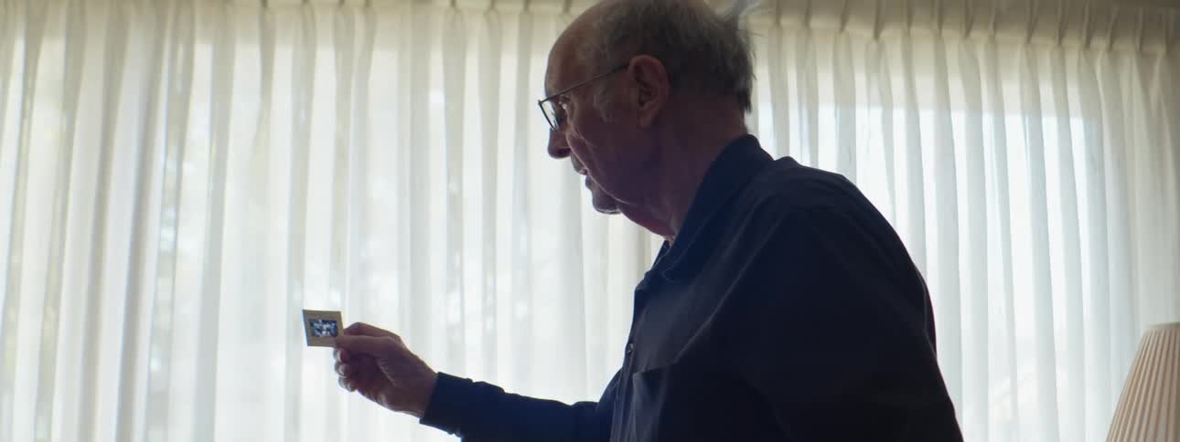 An elderly man looking at a picture slide in a living room