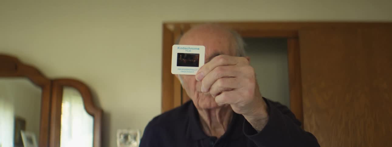 A man holding up an image slide in a room