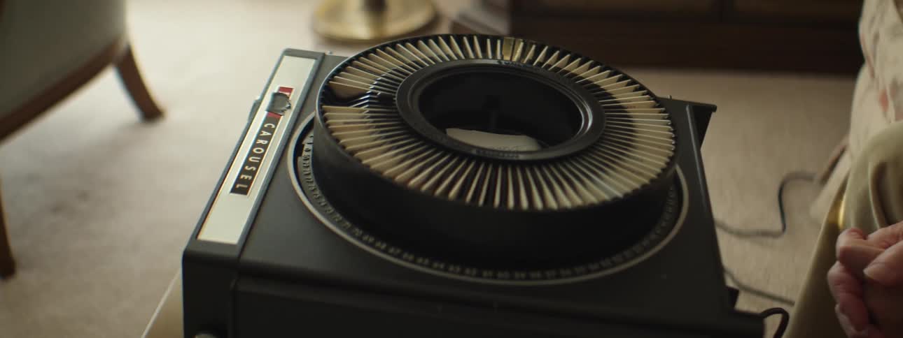 A person sits on a couch watching slides from a slide projector