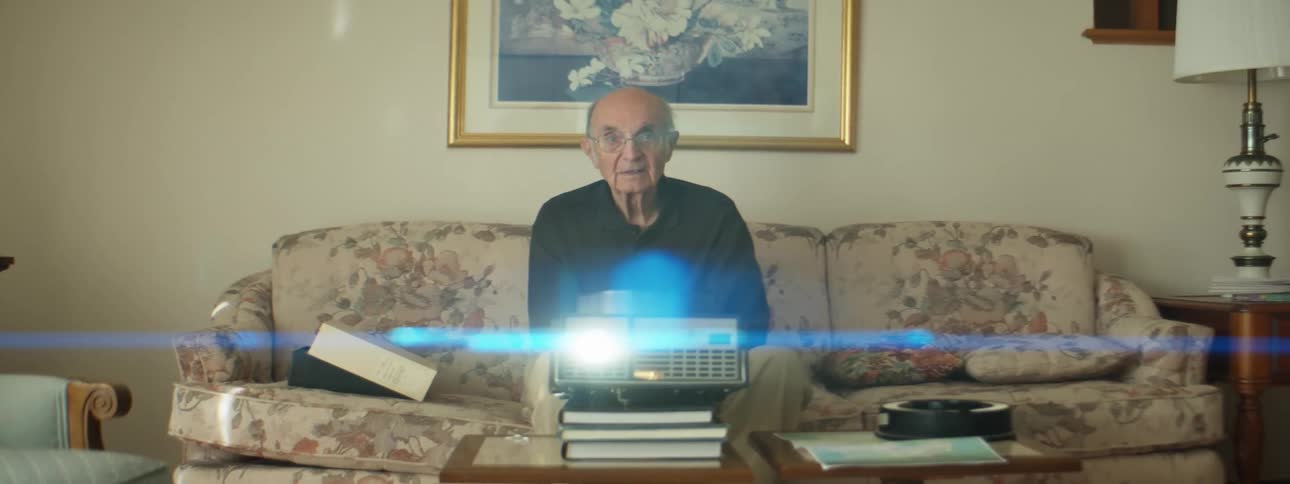 A man that is sitting on a couch with a projector in front of him