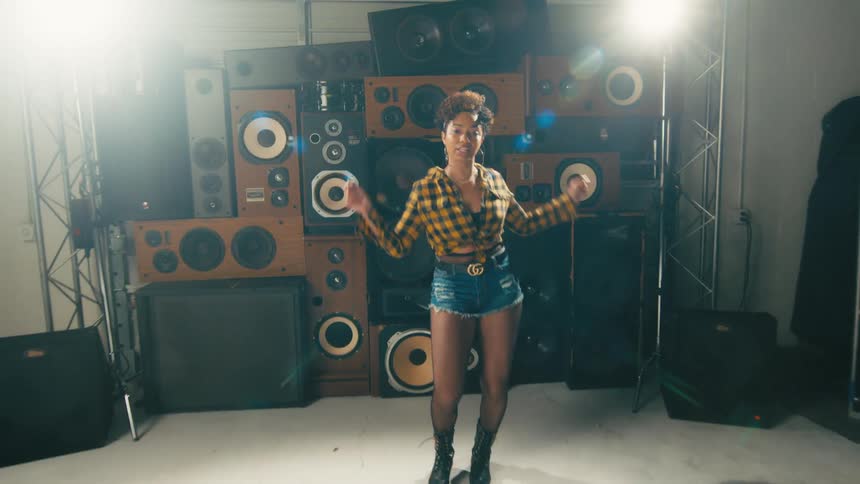 Young woman energetically dancing in front of a tower of speakers