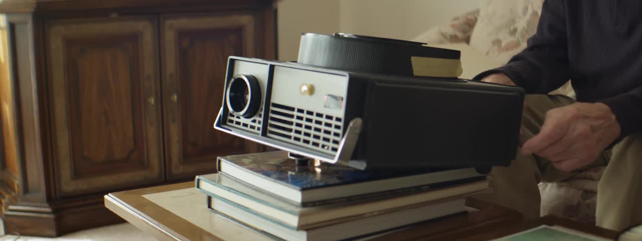 A person sitting on a couch with a projector on books on a table