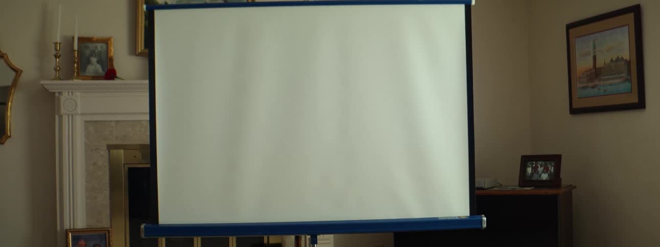 A room with a projector screen with a fireplace candles and a wall in the background