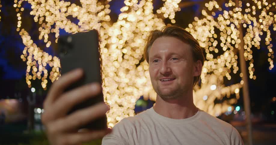 A man that is talking on a smartphone at night